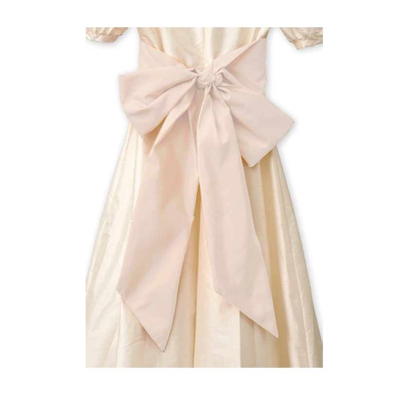 A shel pink sash tied around a bridesmaids dress - The Little Wedding Company