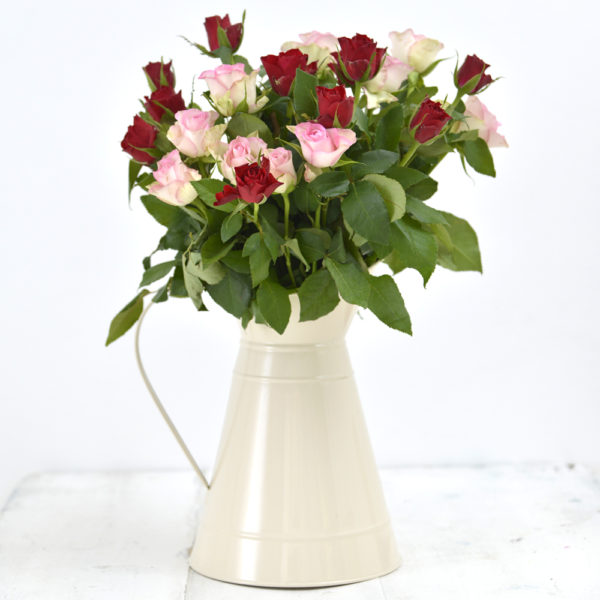 An ivory metal jug with pale pink and rose pink rose in it - The Little Wedding Company