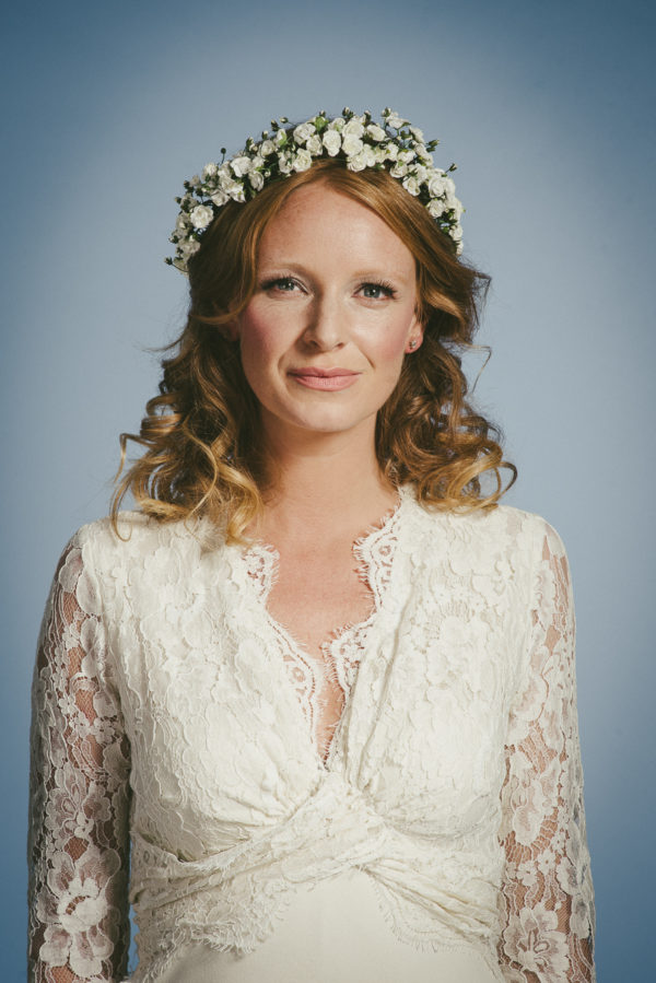 A woman wearing a lace wedding dress with a floral crown with small dleicate ivory flowers - The Little Wedding Company