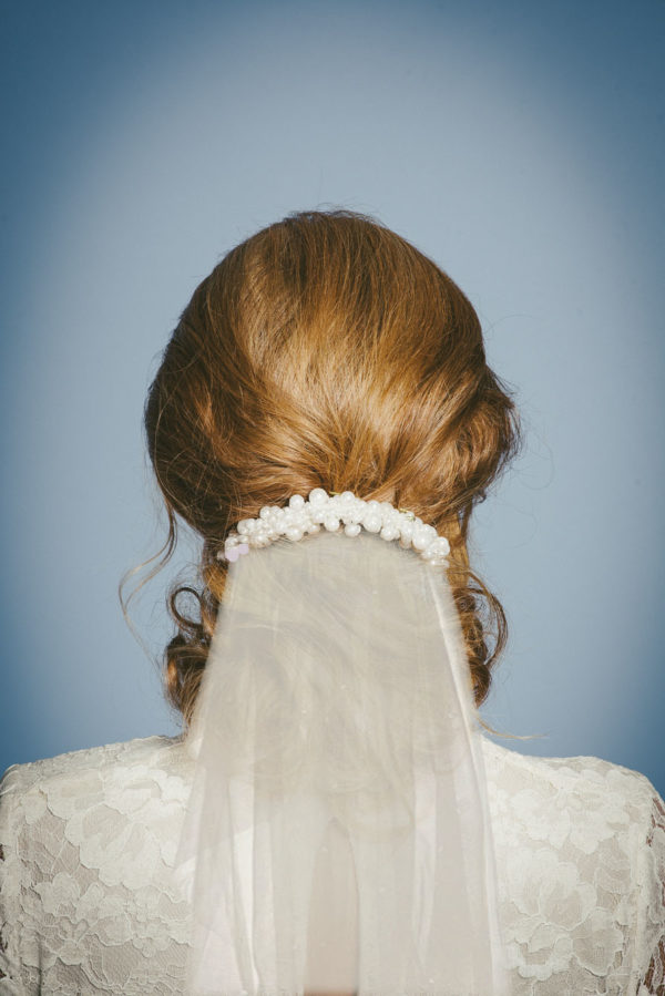 A woman wearing a pearl hairpiece with an ivory veil beneath it - The Little Wedding Company