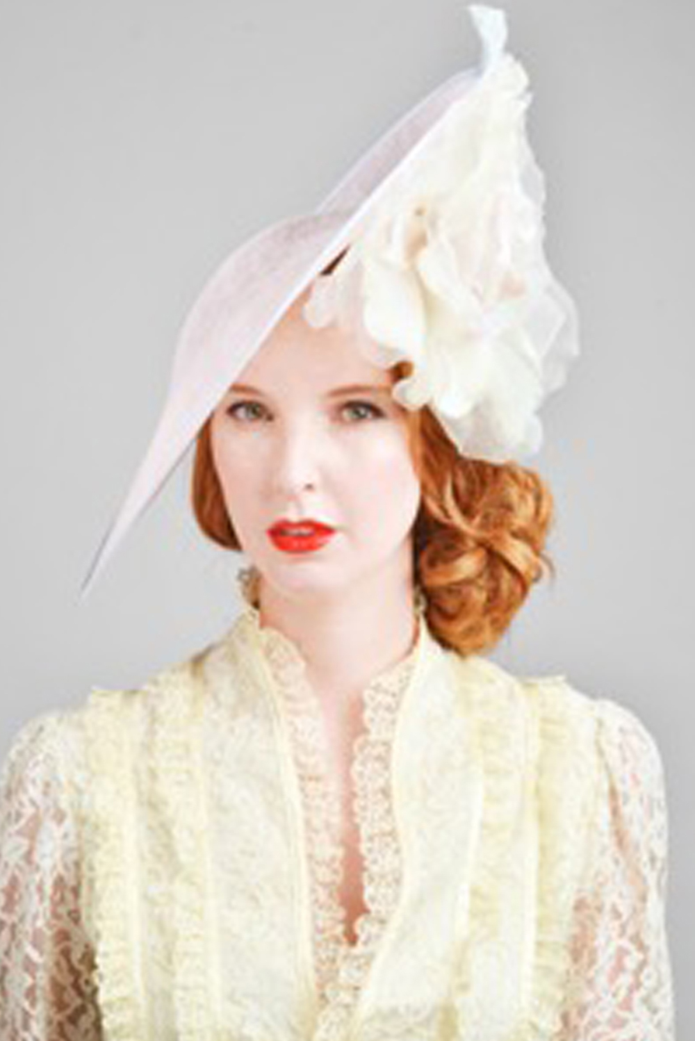 A woman wearing a cream hat with a large cream silk rose - The Little Wedding Company