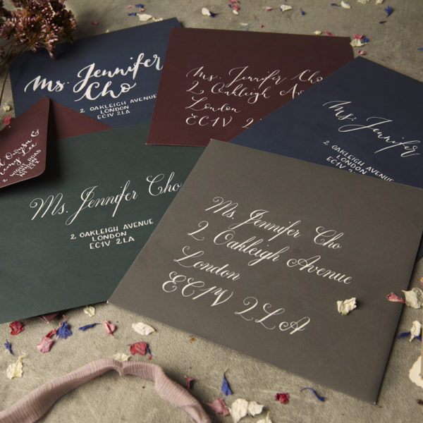 A set of coloured envelopes all with hand written calligraphy address - The Little Wedding Company