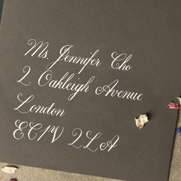 Close up of a grey envelope with handwritten copperplate style calligraphy address - The Little Wedding Company