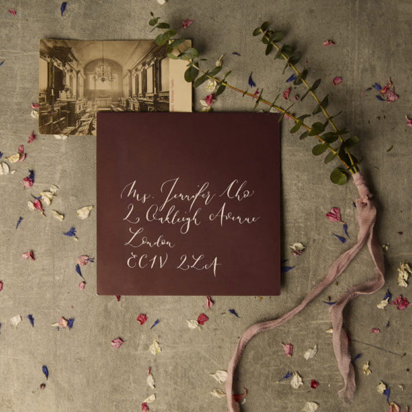 A picture of a red envelope with handwritten calligraphy address - The Little Wedding Company